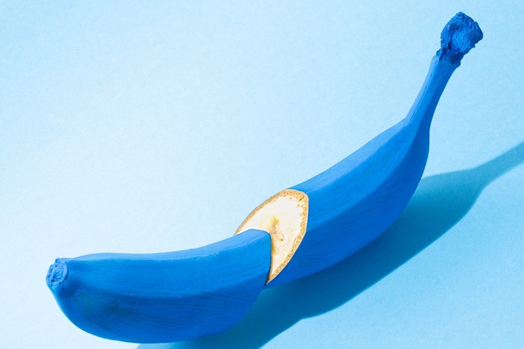 kék háttér előtt egy kékre festett, félbe vágott banán