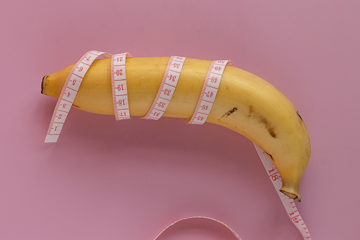 yellow banana wrapped in measure tape. men penis size concept. isolated on pink background