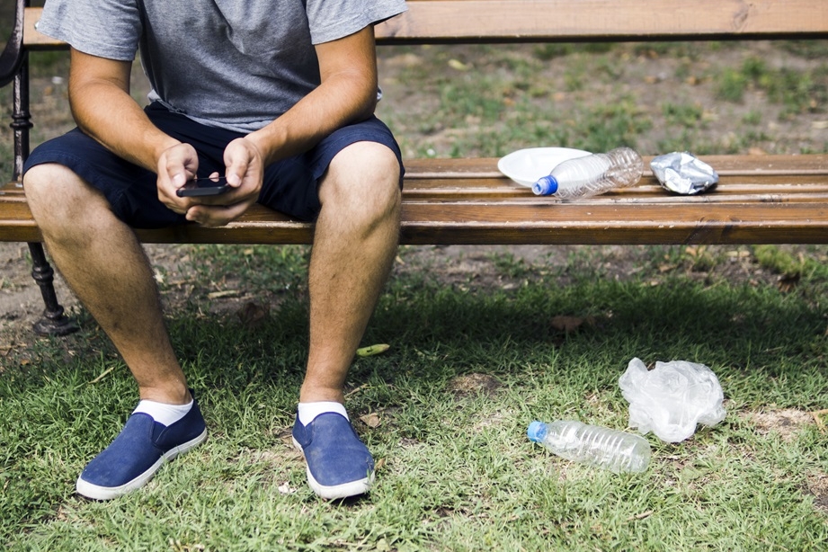Férfi ül egy padon, körülötte a földön műanyag palackok