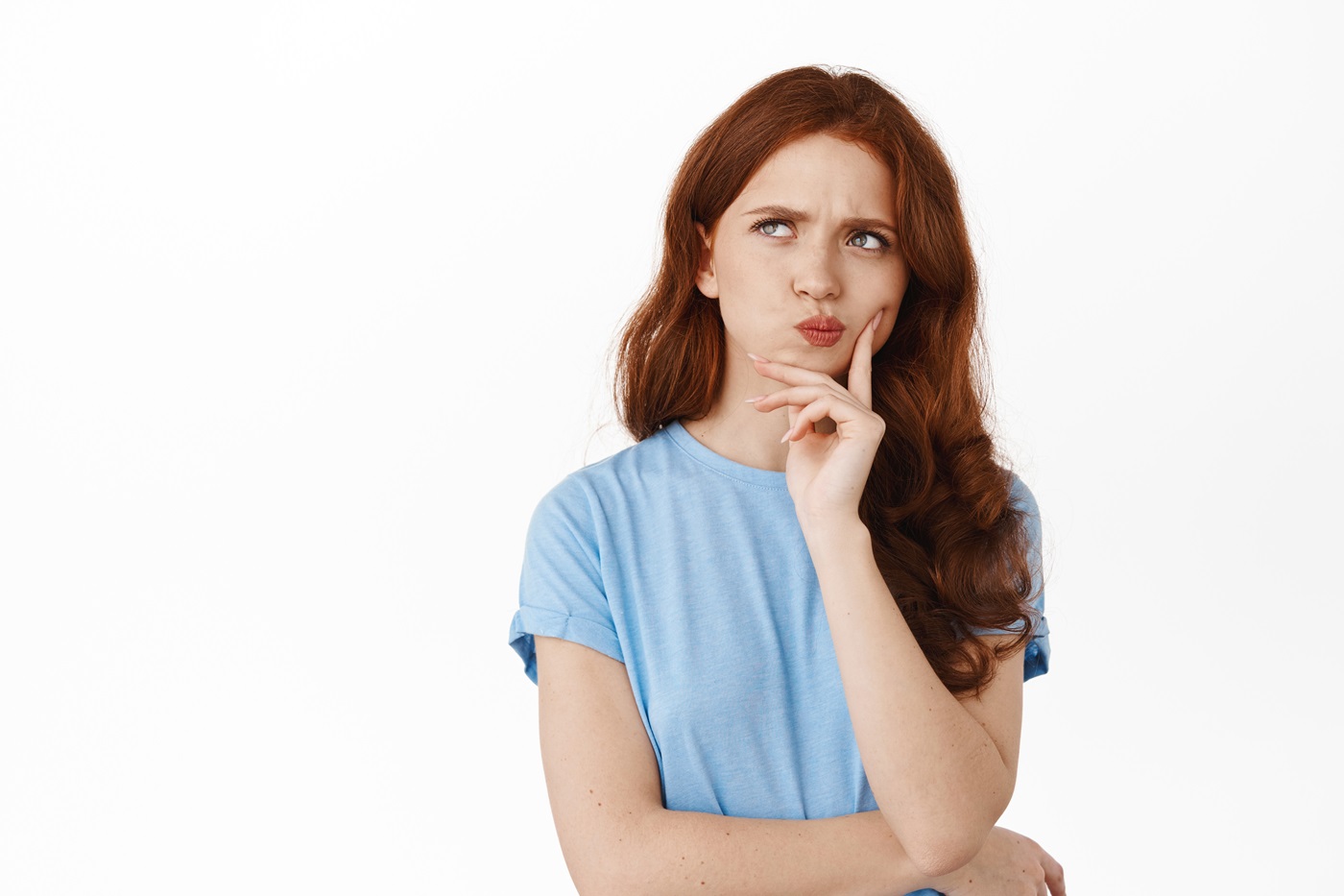 image of thoughtful hesitant girl with red hair making decision, frowning perplexed and thinking, touching lip pondering, standing against white background