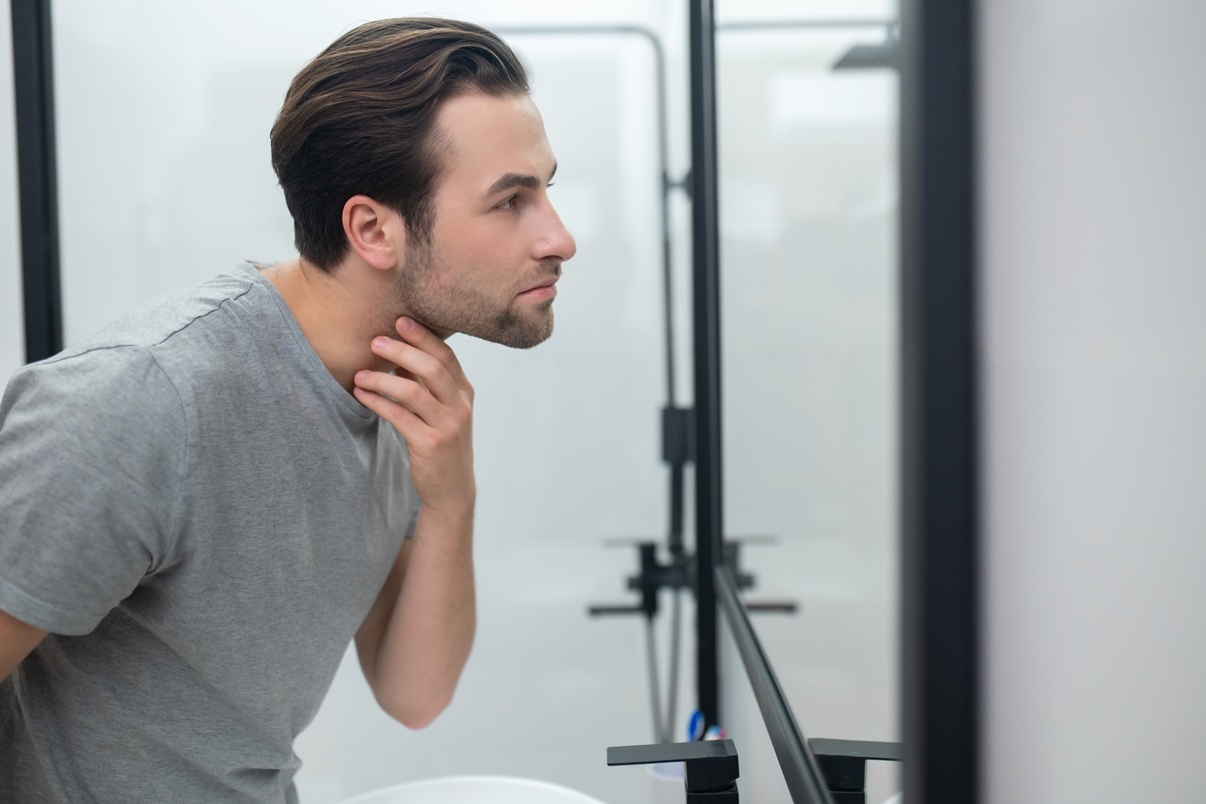 man near the mirror scrutinizing himself