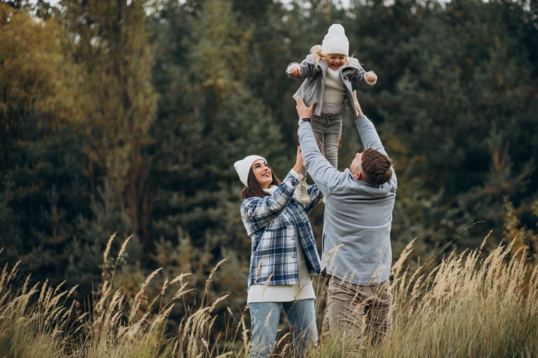 family with little daughter together in autumnal weather having fun