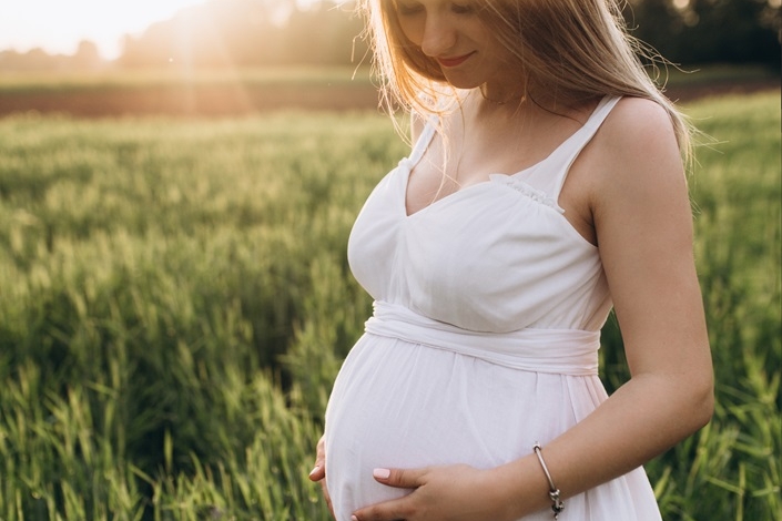 the pregnant girl stands on the fiield